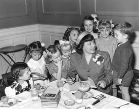 Betty MacDonald signing book with eight children watching.